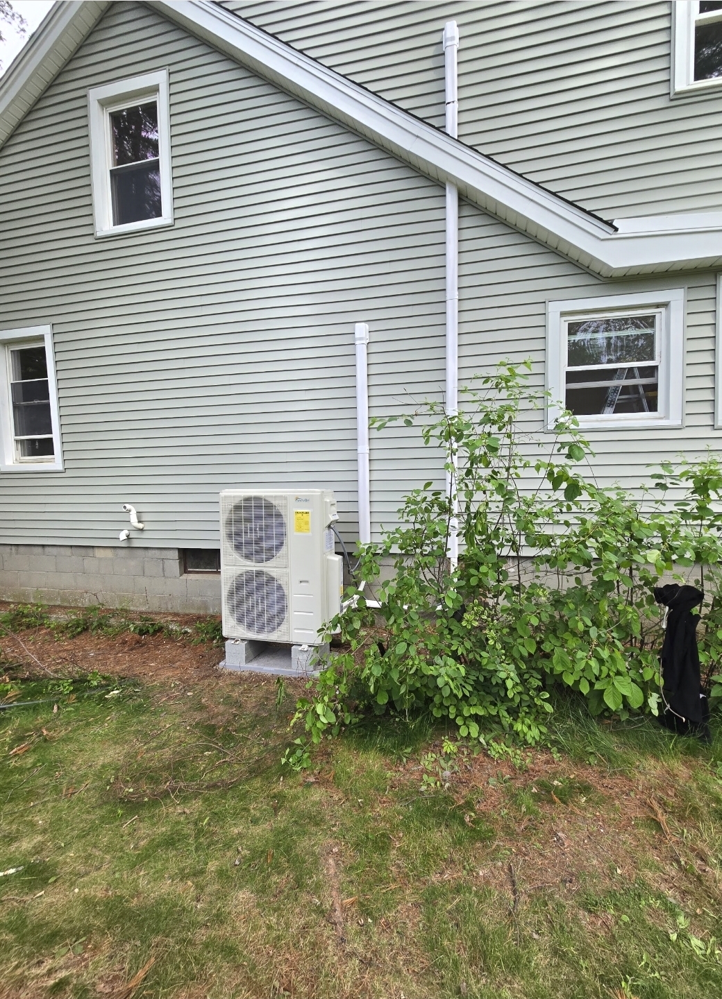 Dual-fan heat pump on ground risers with line-set covers running up the siding